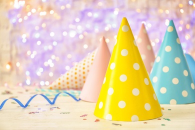 Birthday party caps on table against blurred lights