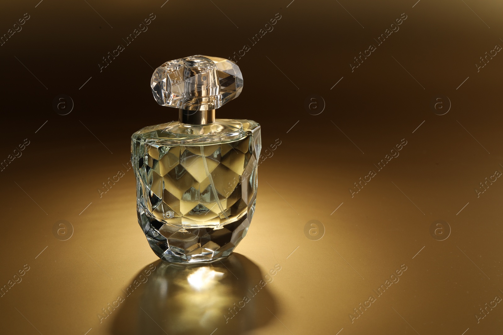 Photo of Luxury women's perfume. Sunlit glass bottle on golden background, space for text