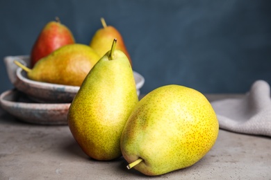 Ripe juicy pears on grey stone table against blue background