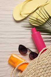Flat lay composition with wicker bag and other beach accessories on sand