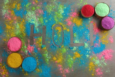 Photo of Word Holi and colorful powder dyes on grey background, flat lay