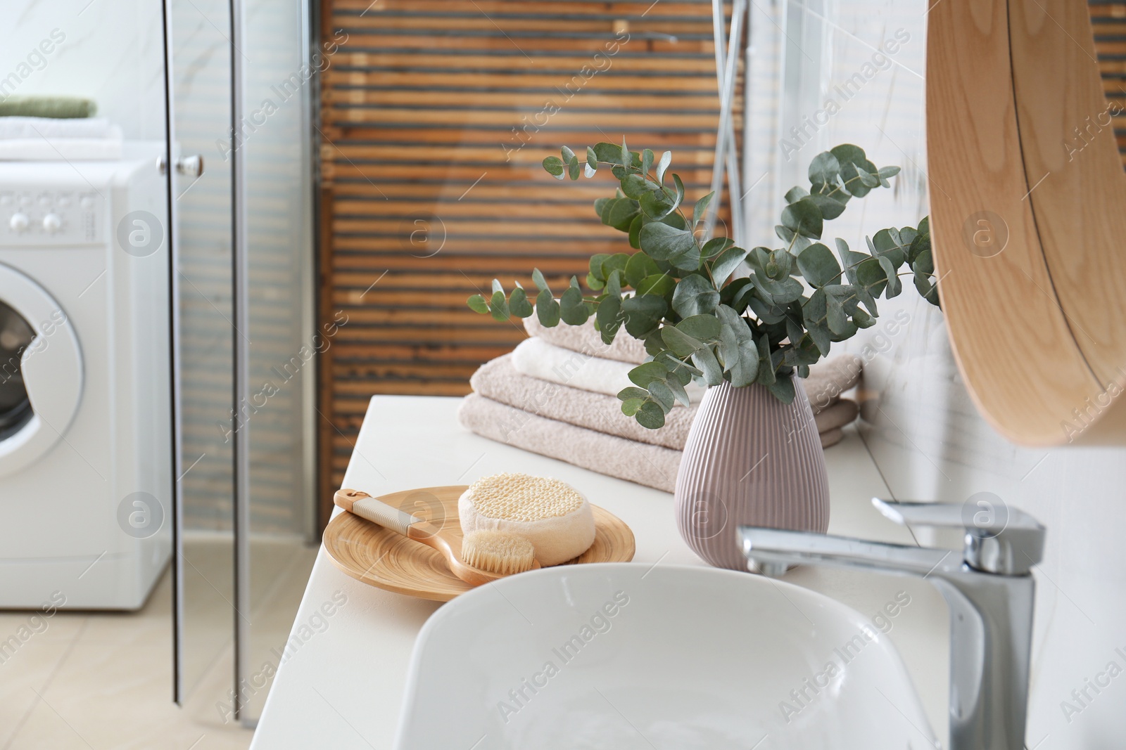 Photo of Fresh eucalyptus branches and bathroom items on countertop