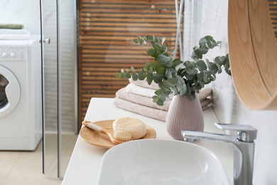 Fresh eucalyptus branches and bathroom items on countertop