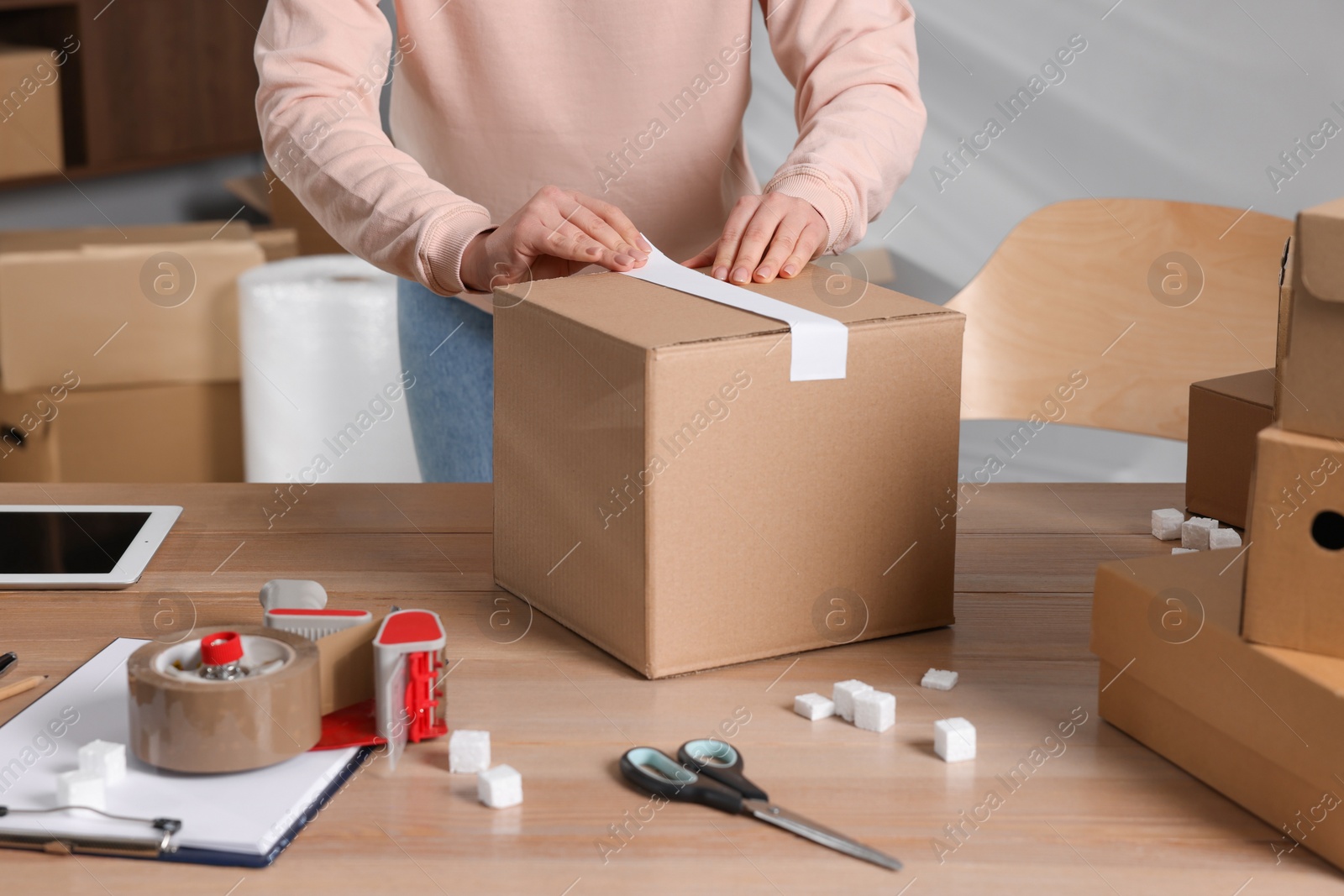 Photo of Seller taping parcel at workplace, closeup. Online store