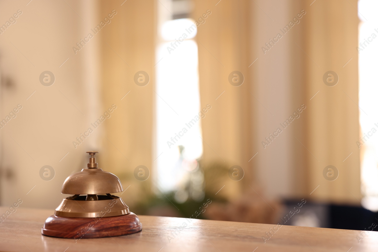 Photo of Hotel service bell on wooden reception desk. Space for text