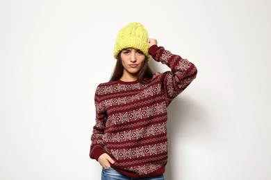 Young woman in warm sweater and knitted hat on white background. Celebrating Christmas