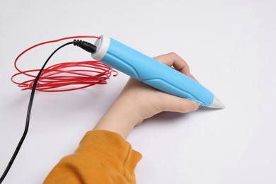 Photo of Boy drawing with stylish 3D pen on white background, closeup