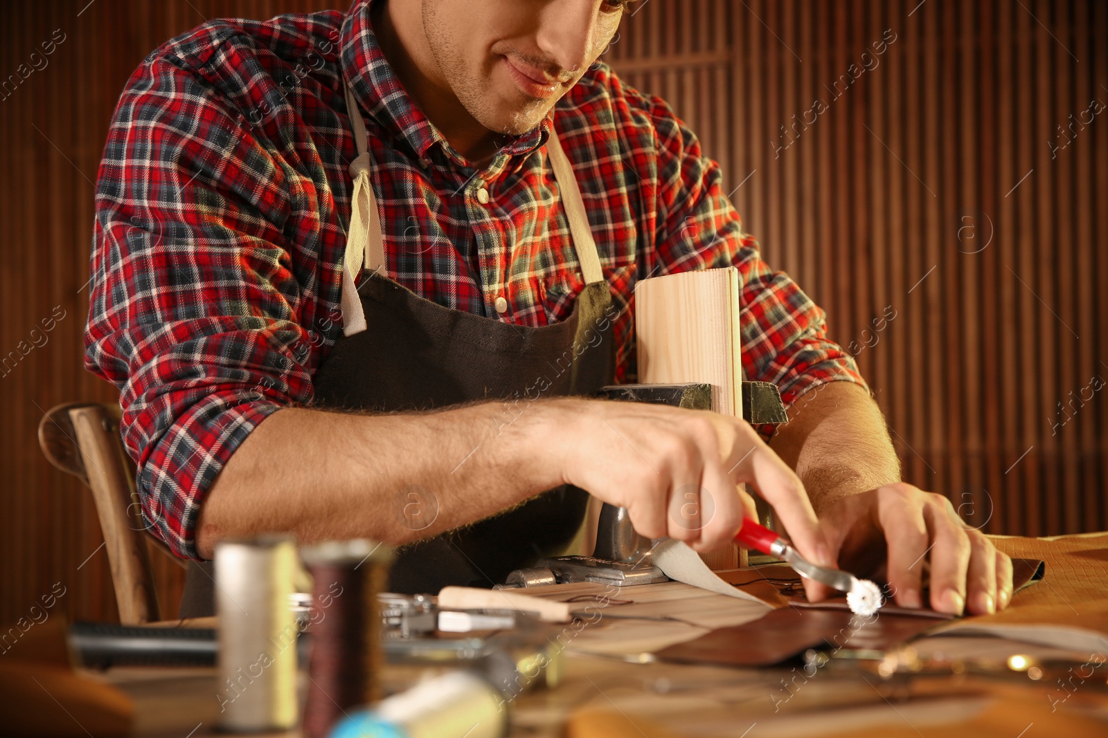 Photo of Man marking leather with roller in workshop, closeup