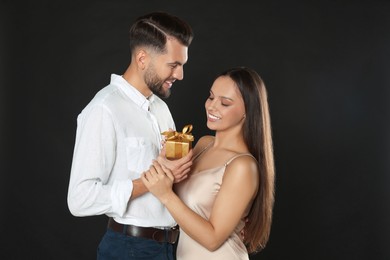 Photo of Lovely couple with gift on black background