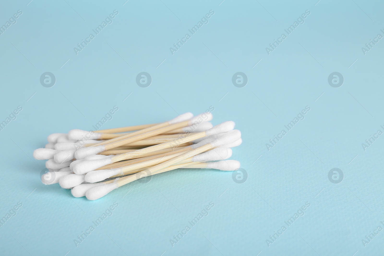 Photo of Wooden cotton buds on light blue background. Space for text