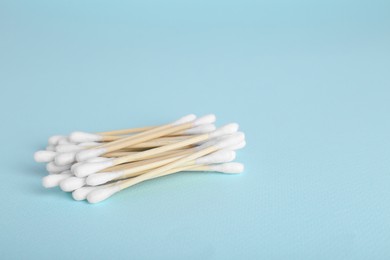 Wooden cotton buds on light blue background. Space for text