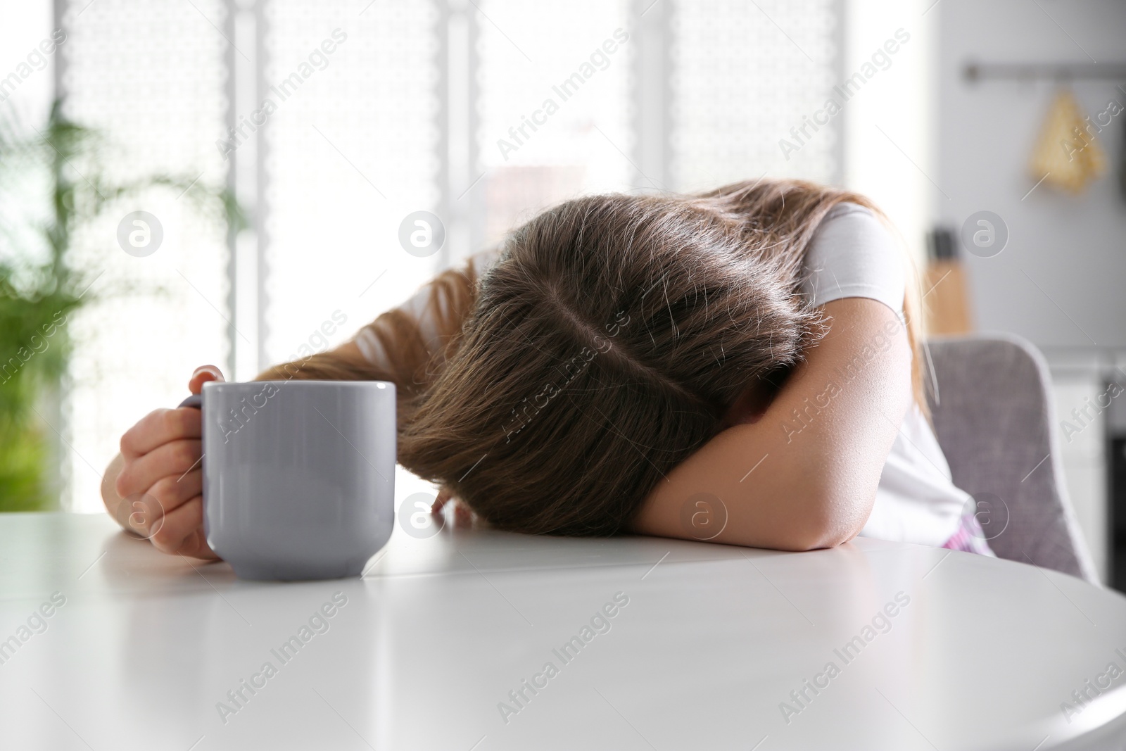 Photo of Young woman with cup of drink sleeping at home in morning