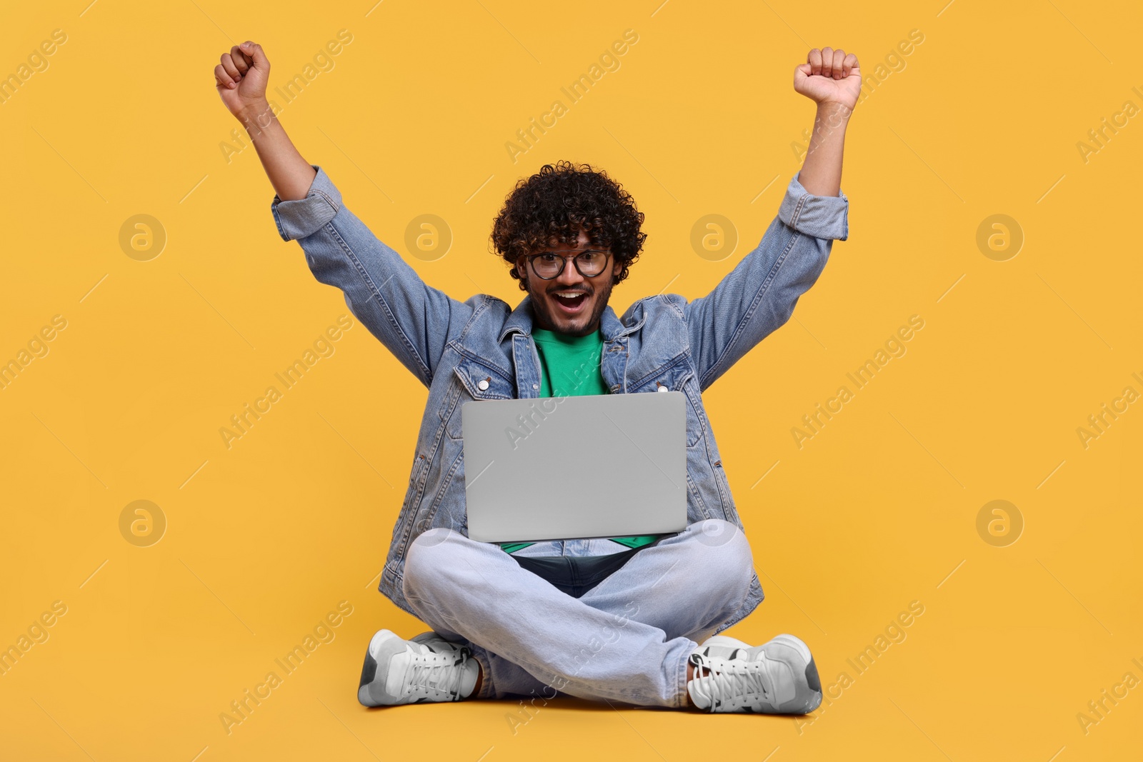 Photo of Happy man with laptop on yellow background