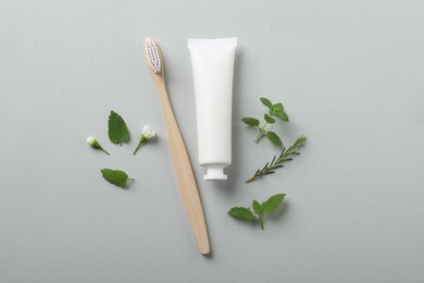 Flat lay composition with toothbrush, toothpaste and herbs on light grey background
