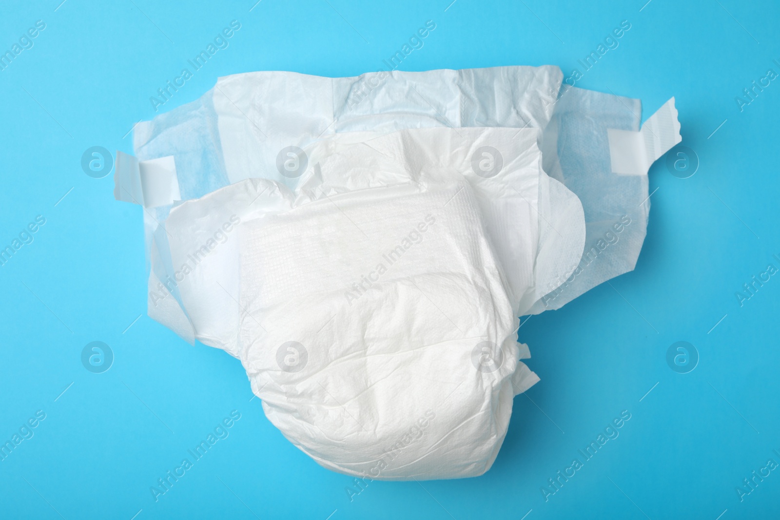 Photo of Baby diaper on light blue background, top view