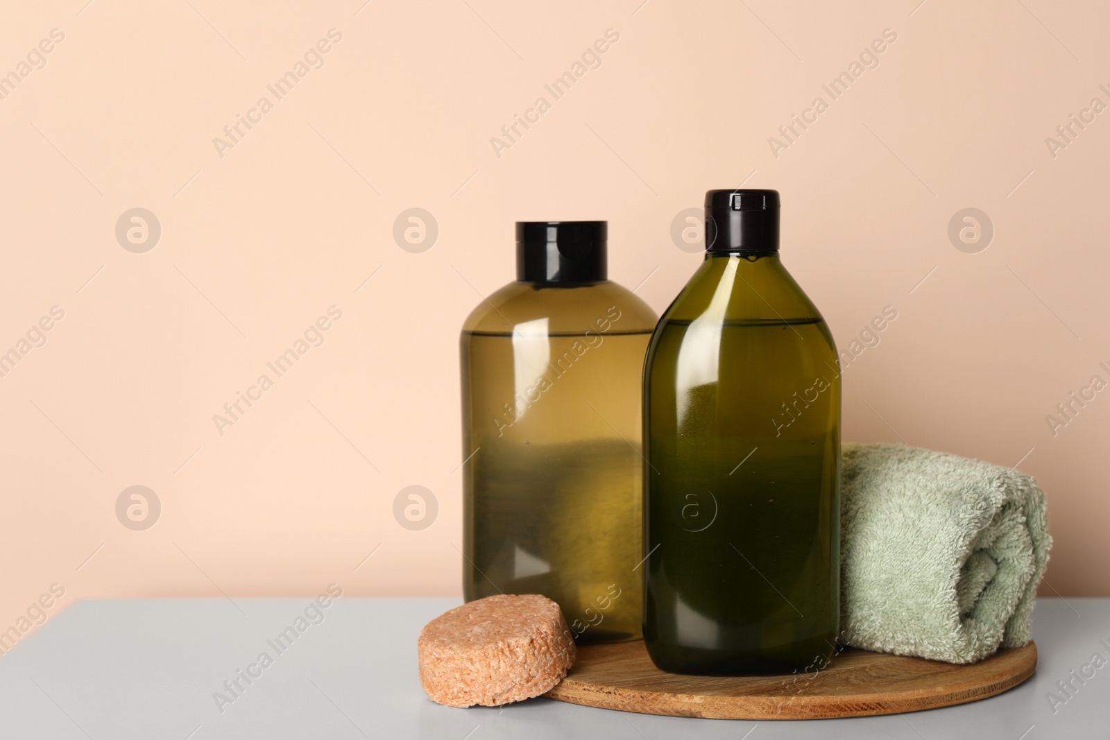 Photo of Solid shampoo bar and bottles of cosmetic product on white table, space for text