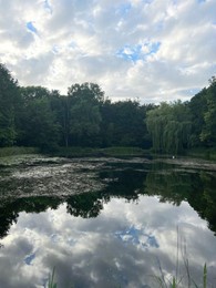 Photo of Picturesque view of green park with lake on cloudy day