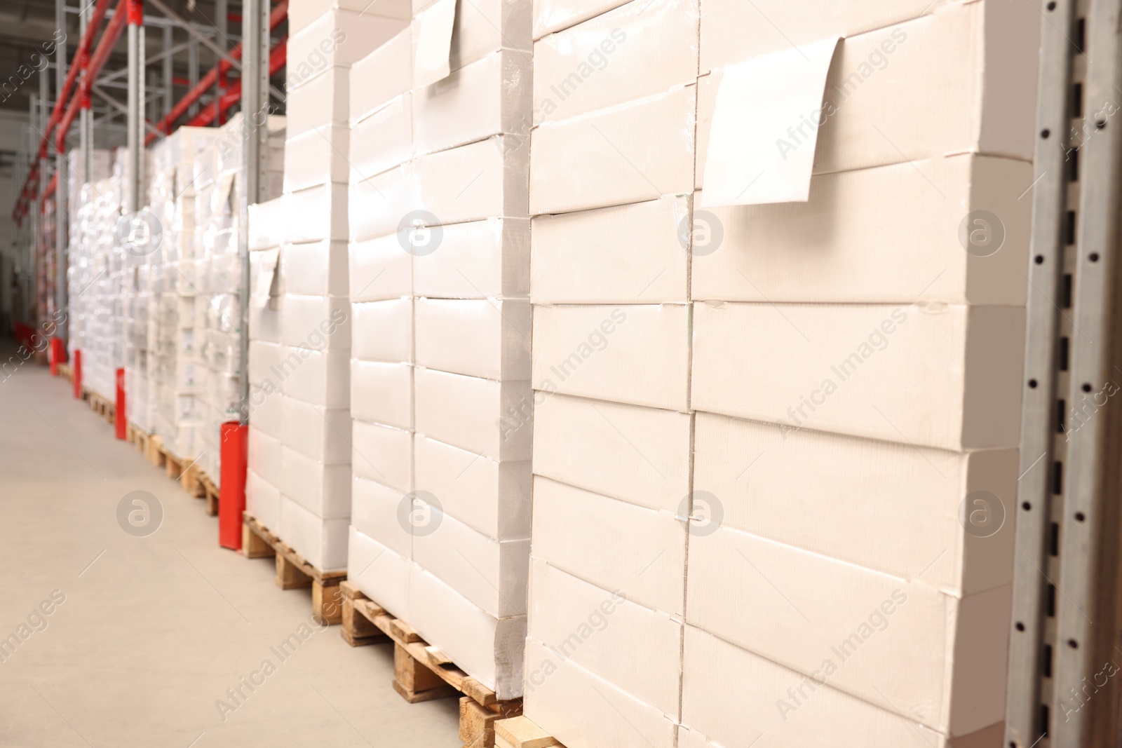 Photo of Warehouse with stacks of boxes on wooden pallets. Wholesaling