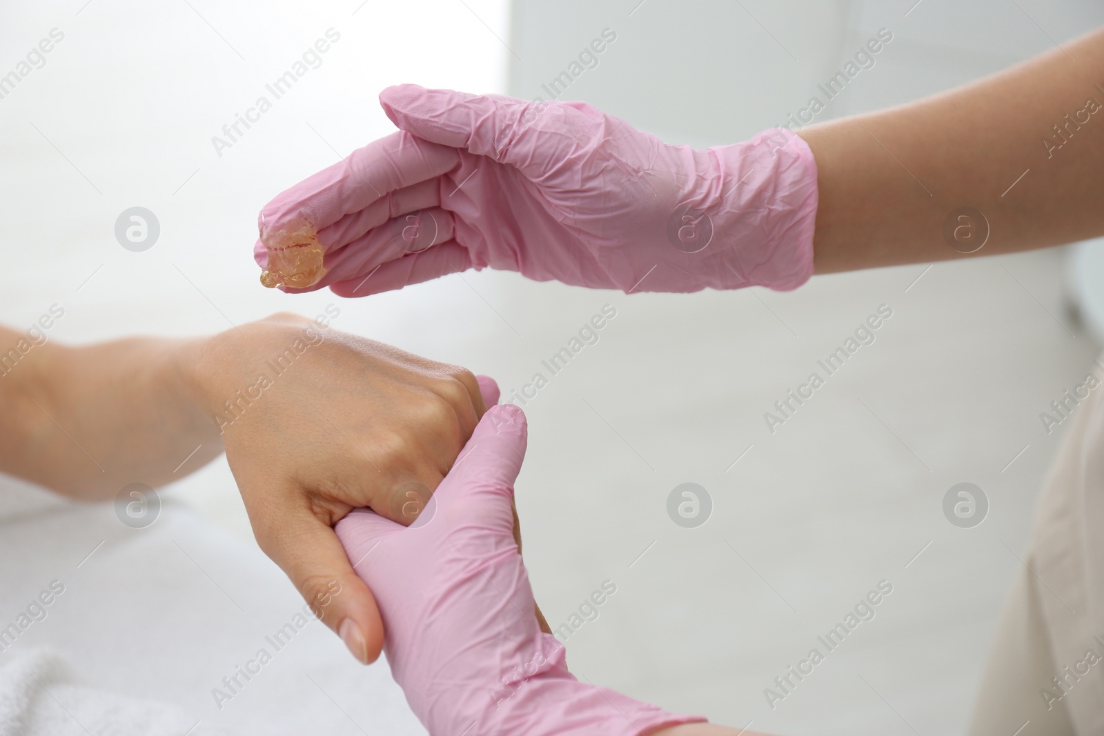 Photo of Woman getting wax epilation of hand in salon, closeup