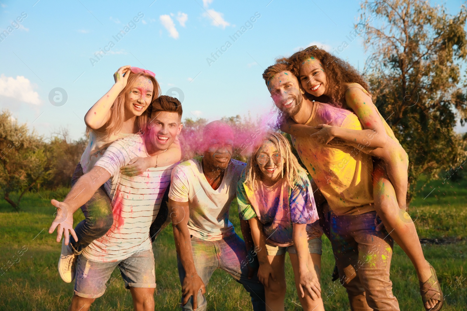 Photo of Happy friends covered with colorful powder dyes outdoors. Holi festival celebration