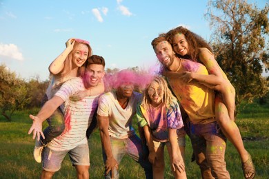 Photo of Happy friends covered with colorful powder dyes outdoors. Holi festival celebration