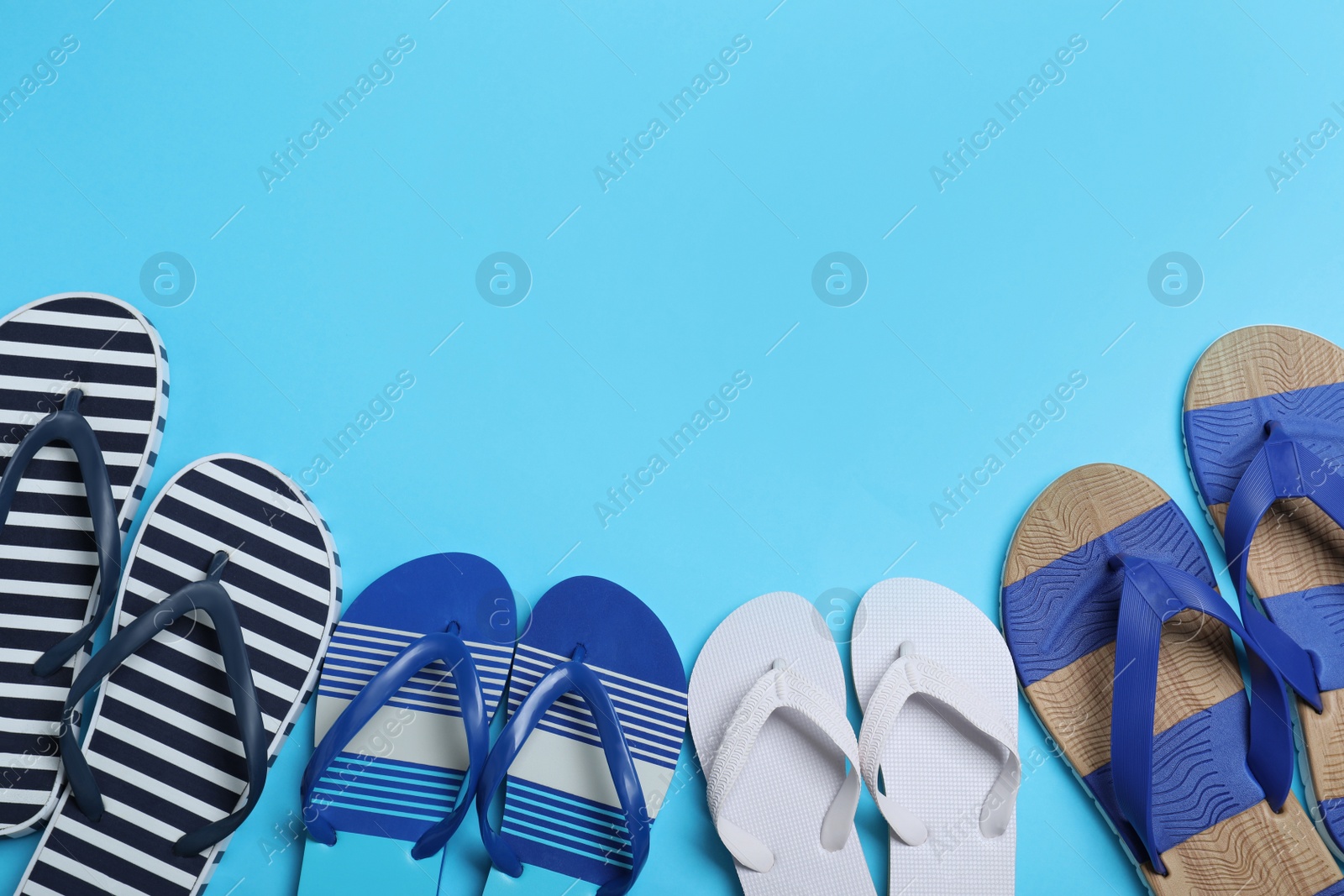 Photo of Many different stylish flip flops on light blue background, flat lay. Space for text