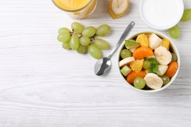 Photo of Delicious fresh fruit salad in bowl on white wooden table, flat lay. Space for text