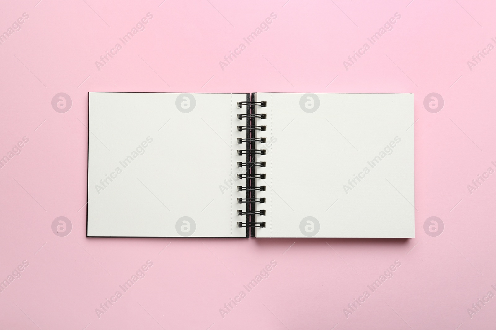 Photo of Open notebook on pink background, top view