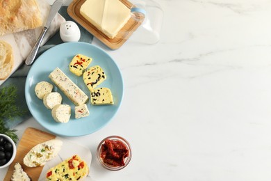 Photo of Different types of tasty butter, dill, chili and bread on white marble table, top view. Space for text