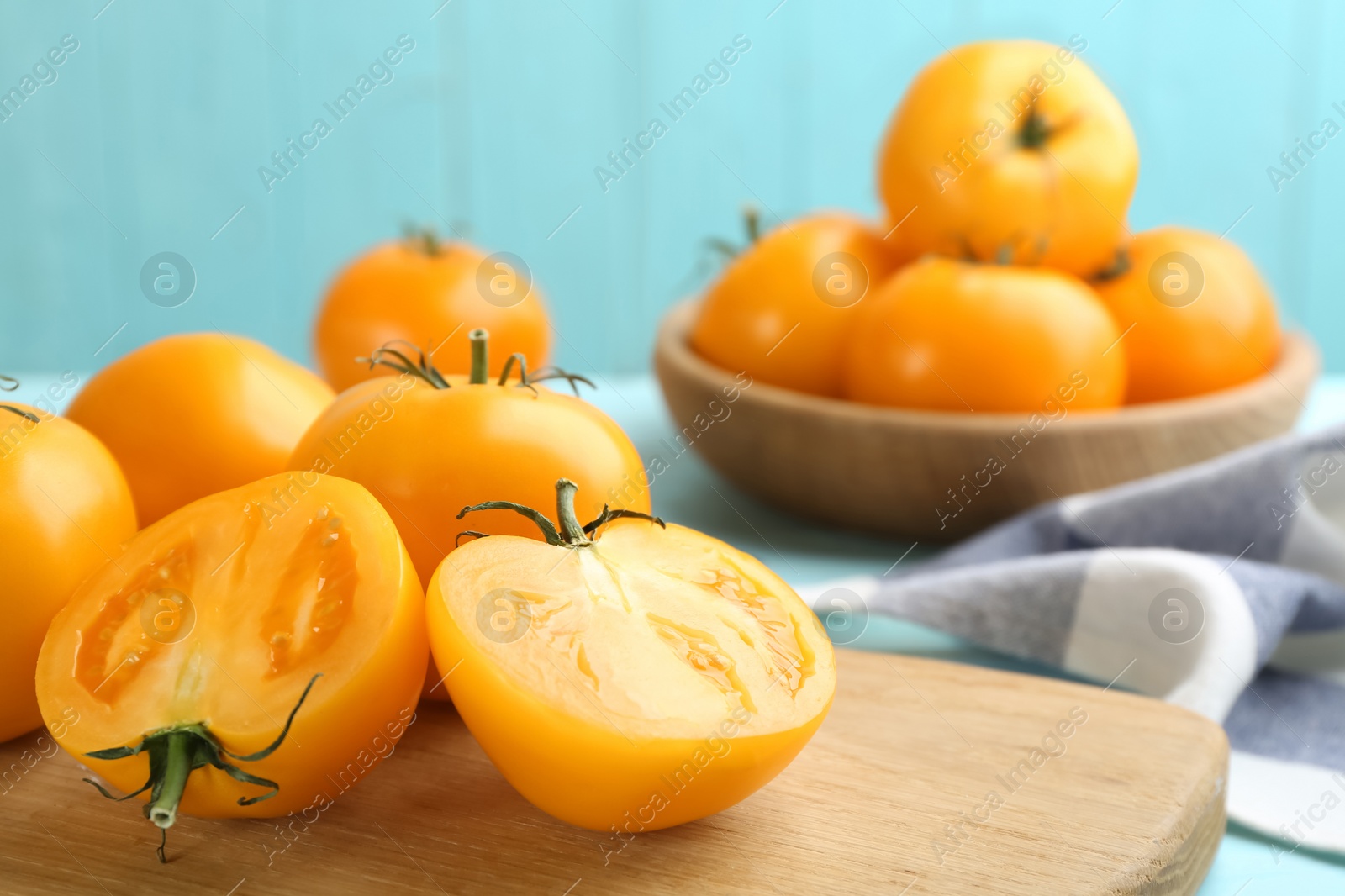 Photo of Ripe yellow tomatoes on wooden board, closeup