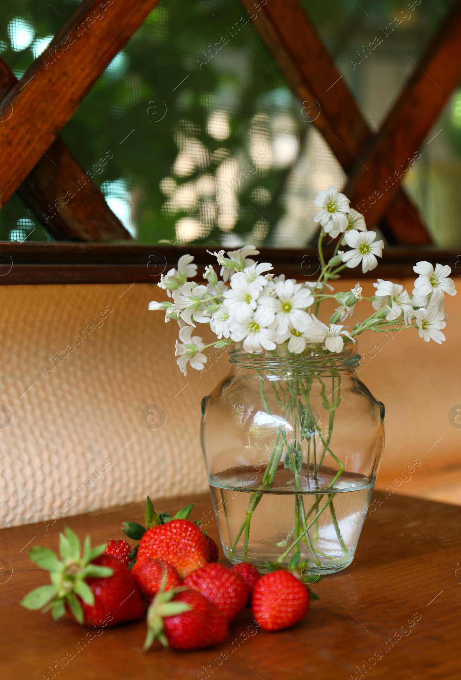 Photo of Fresh strawberries and bouquet of beautiful white flowers on wooden table
