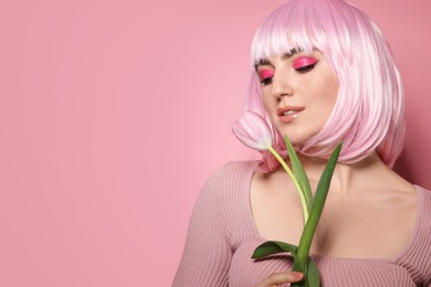 Photo of Beautiful woman with bright makeup, fake freckles and tulip on pink background. Space for text