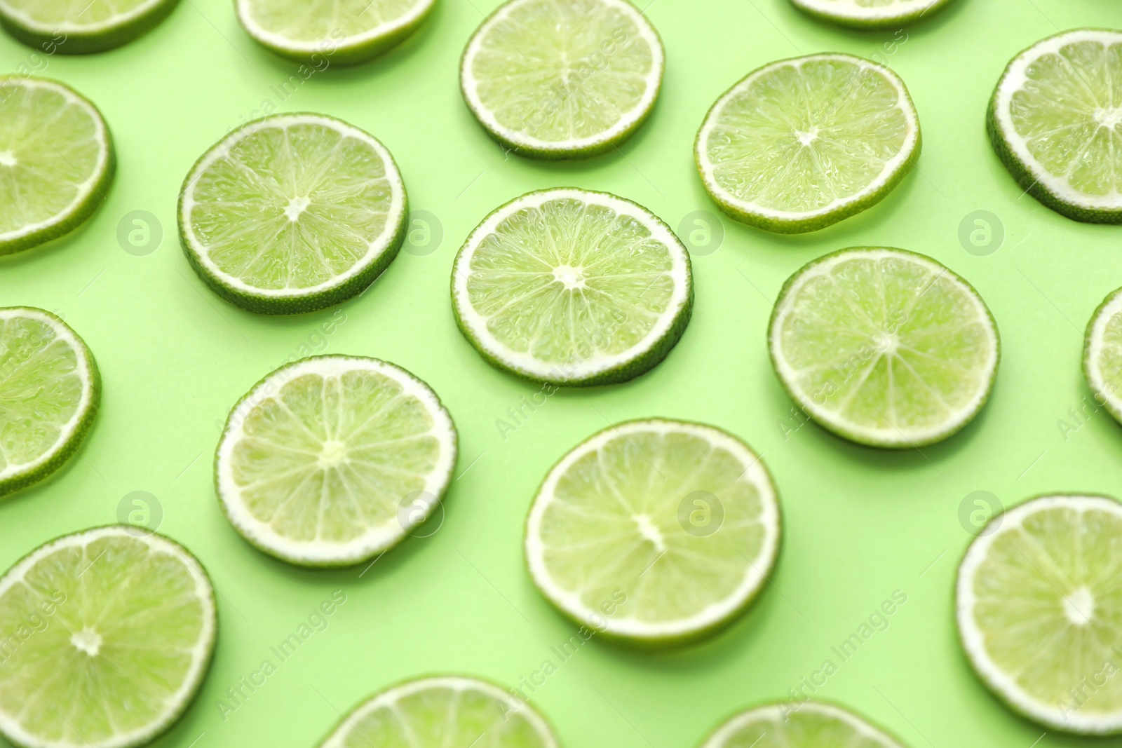 Photo of Slices of fresh juicy limes on green background