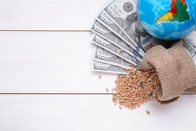 Photo of Globe, bag of wheat grains and money on white wooden table, flat lay with space for text. Import and export concept