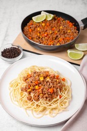 Tasty dish with fried minced meat, spaghetti, carrot and corn on served white textured table