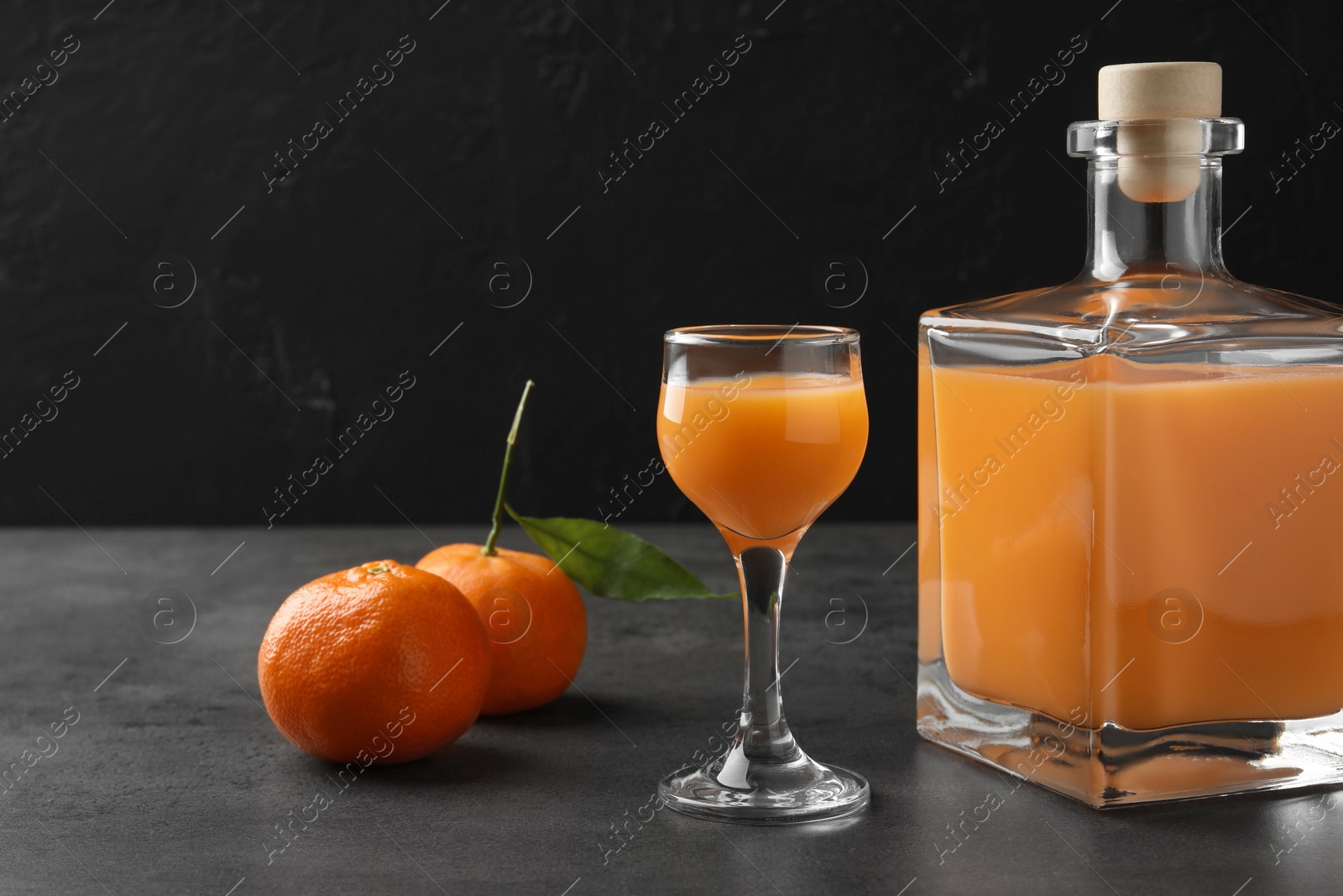 Photo of Delicious tangerine liqueur and fresh fruits on grey table