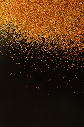 Photo of Gold glitter on black background, top view with space for text