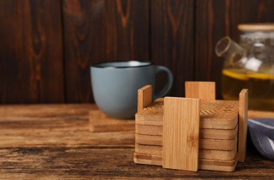 Stylish cup coasters in holder on wooden table, space for text