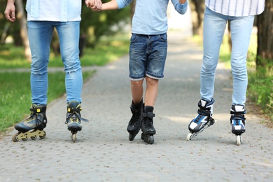 Young family roller skating in park, closeup of legs