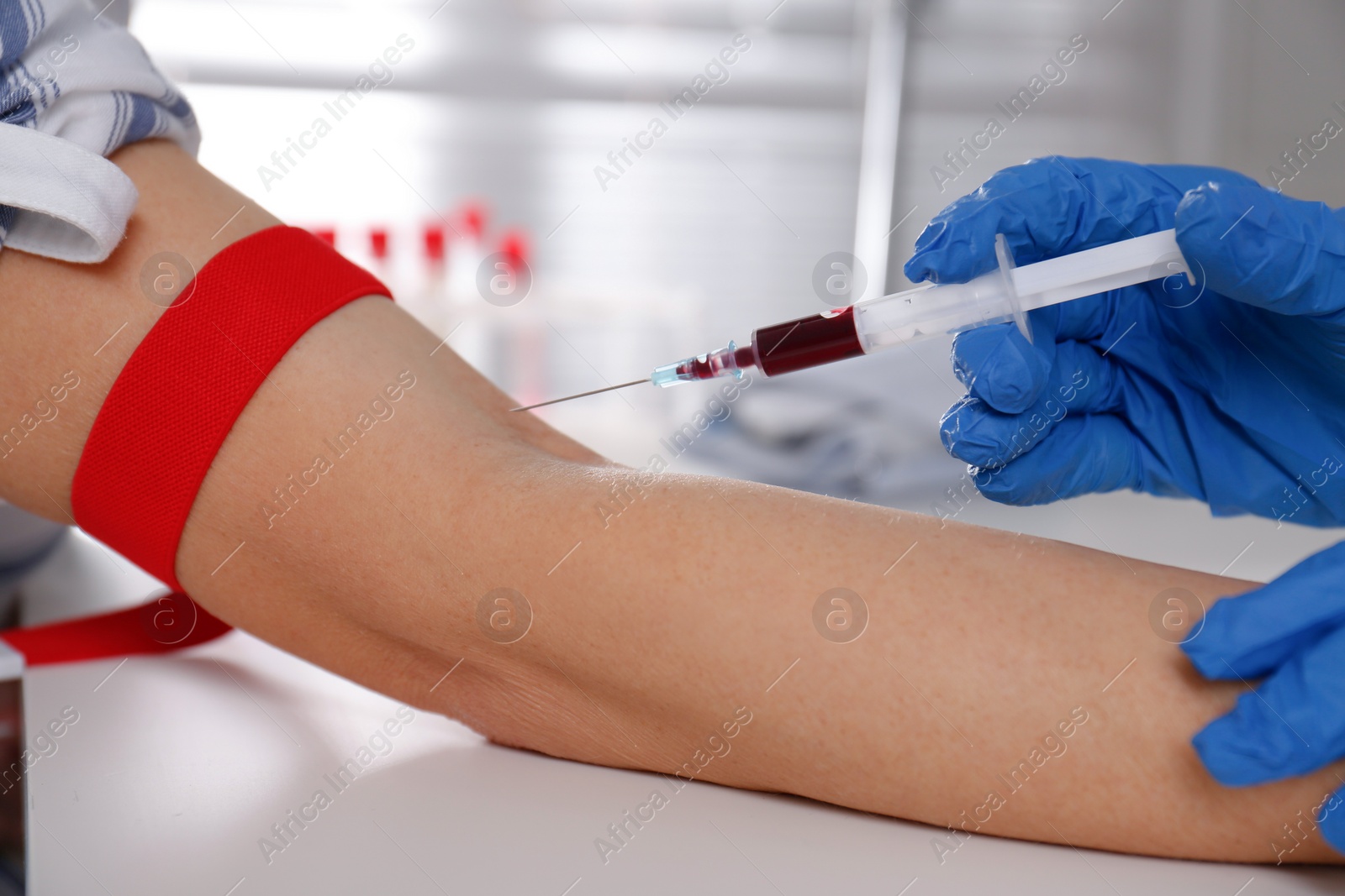 Photo of Nurse drawing blood sample from patient in clinic, closeup