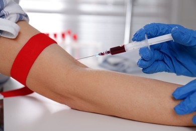 Nurse drawing blood sample from patient in clinic, closeup