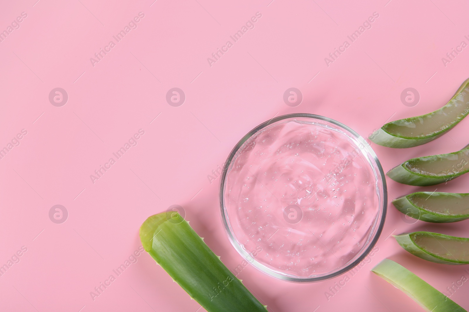 Photo of Aloe vera leaves and cosmetic gel on pink background, top view. Space for text