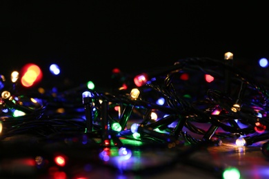 Photo of Colorful Christmas lights on table, closeup view