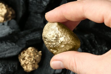 Photo of Woman holding gold nugget on blurred background, closeup. Space for text