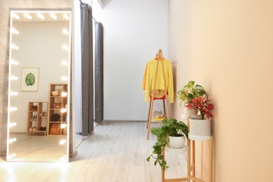 Photo of Stylish dressing room interior with mirror and clothing rack