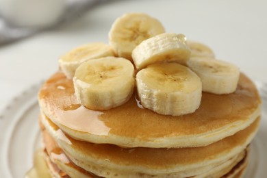 Photo of Delicious pancakes with bananas and honey on white table, closeup