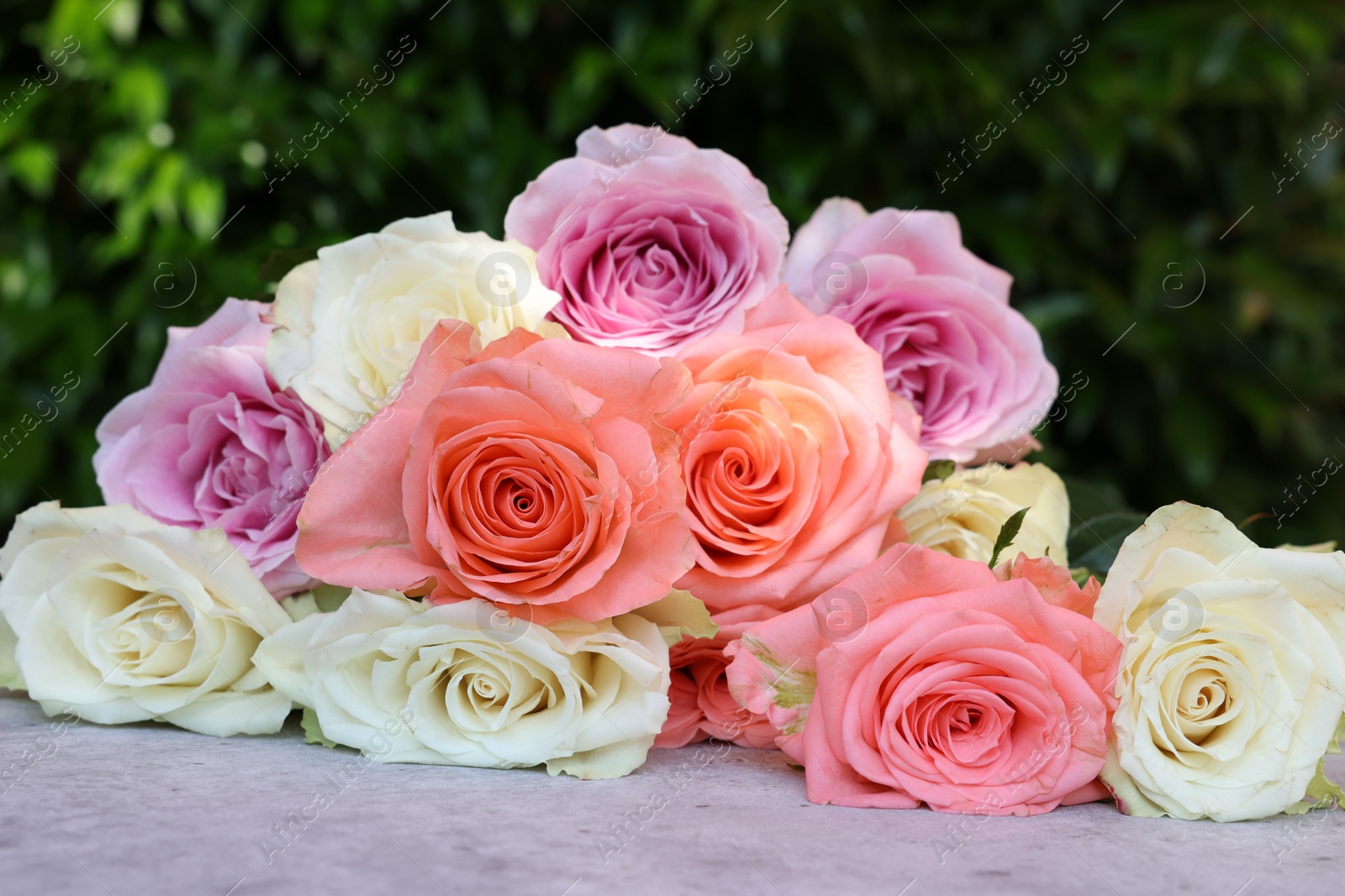 Photo of Beautiful bouquet of roses on light grey table outdoors, closeup