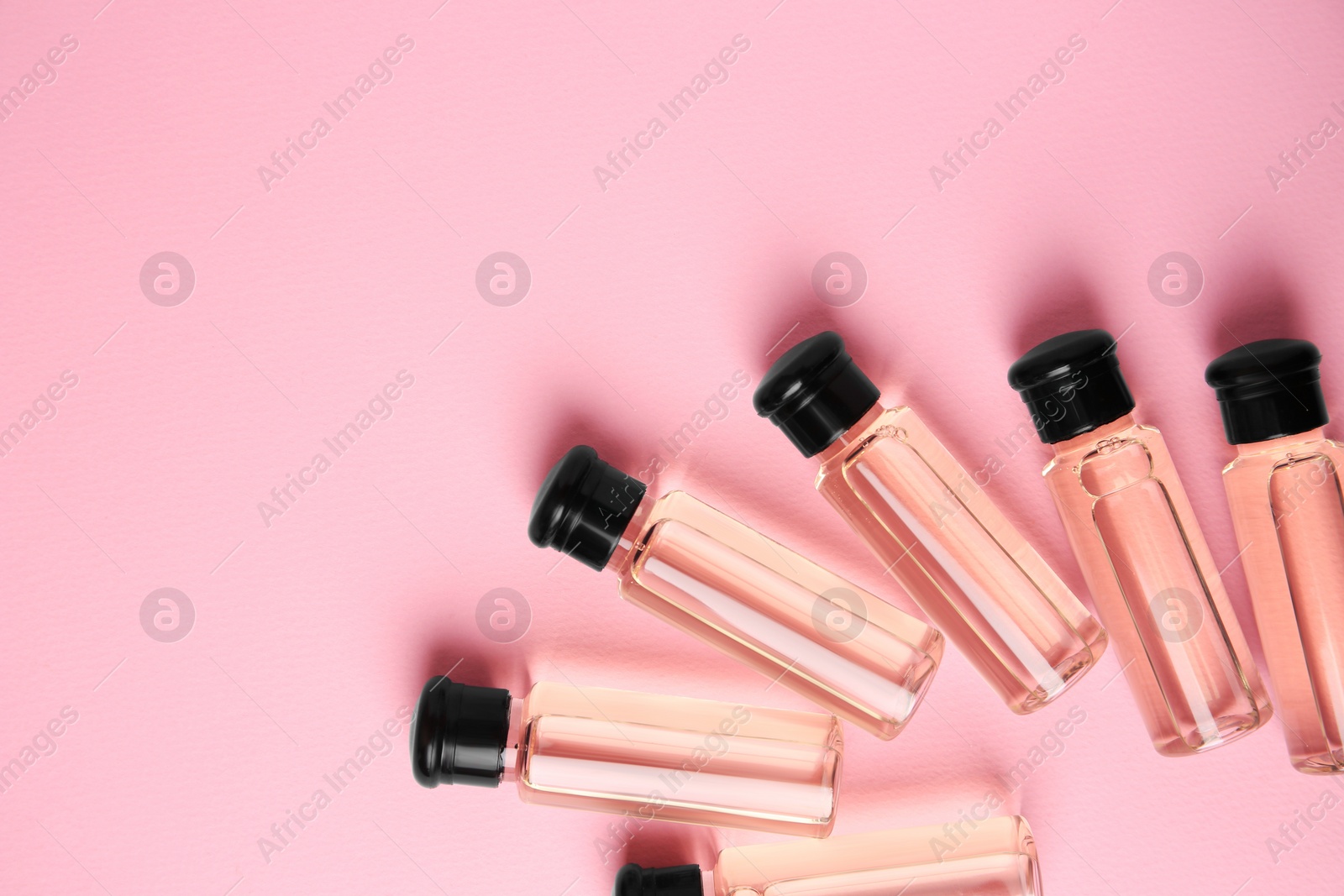 Photo of Bottles of cosmetic products on pink background, flat lay. Space for text