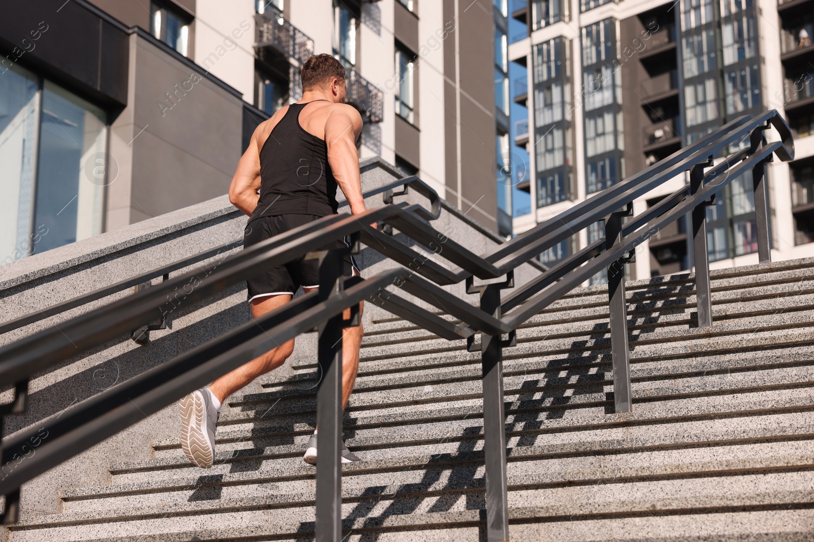 Photo of Man running up stairs outdoors on sunny day, low angle view