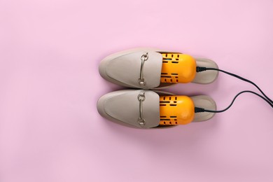 Pair of stylish shoes with modern electric footwear dryer on pink background, top view. Space for text